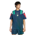 A man wearing a navy blue Adidas t-shirt with teal and red color-blocked shoulders and an Italian crest, paired with matching striped shorts.