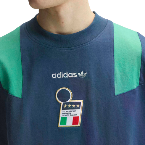 Close-up of a navy blue Adidas shirt with green shoulder panels, featuring the Adidas logo and the Italian national football team crest with four stars.