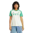 A person wears a white and green soccer jersey with a "YETI" logo and blue jeans against a black background.