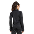 A woman with long, dark, curly hair in a high ponytail stands facing away, wearing a black athletic jacket and matching pants against a plain white background.