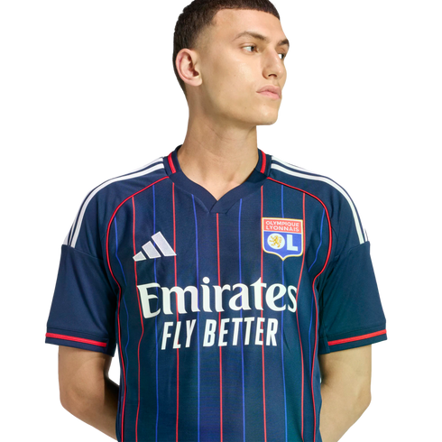 Male model wearing a navy blue Olympique Lyonnais soccer jersey with thin red stripes and white Adidas and Emirates logos.