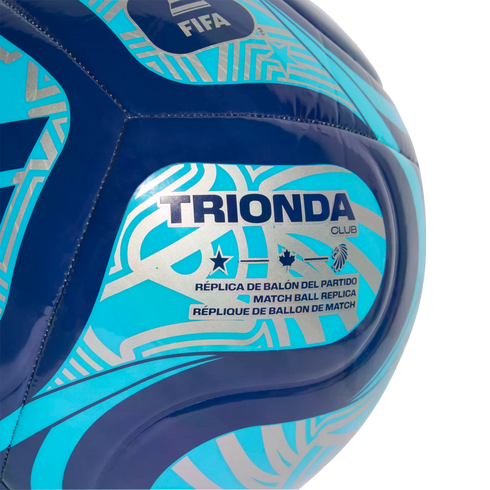 Close-up of a blue and turquoise soccer ball with silver patterns. Text reads "TRIONDA CLUB" and "MATCH BALL REPLICA" alongside FIFA, star, maple leaf, and lion head logos.