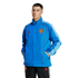 A man models a blue Adidas Manchester United track jacket and black track pants against a plain white background. The jacket features white stripes and red accents.