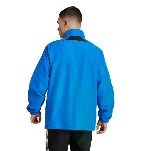 Rear view of a man wearing a bright blue athletic jacket and black striped track pants against a white background.