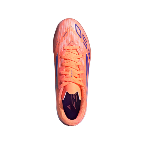 Top-down view of a bright orange Adidas F50 soccer cleat with purple details, set against a black background.