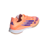 A peach-colored Adidas F50 indoor soccer shoe with navy blue stripes and logo against a black background.