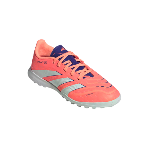 A coral pink Adidas Predator turf soccer shoe with three white stripes and purple accents, angled against a solid black background.