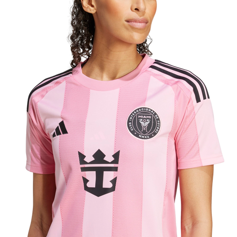 A woman wearing a pink Inter Miami CF soccer jersey featuring the team crest, Adidas logo, and Royal Caribbean sponsorship logo on the front.