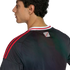 Profile and back view of a man wearing a black sports jersey with red stripes on the shoulders and a small "River Plate" logo on the upper back.