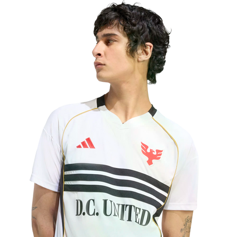 A man in a white D.C. United jersey with black stripes and red logos, looking away in profile against a black background.