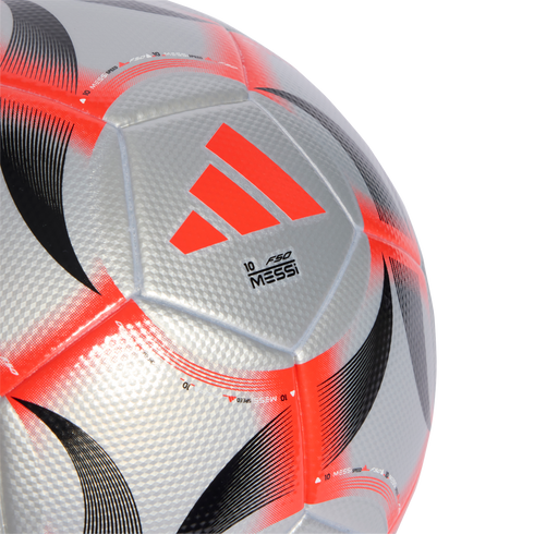 Close-up of a silver Adidas F50 Messi soccer ball with orange and black graphics and a textured diamond pattern on its panels.
