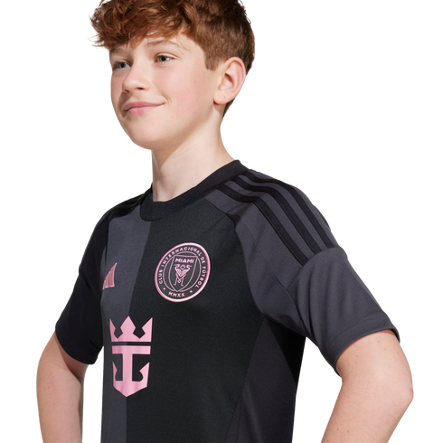A young person with wavy reddish-brown hair wears a black and grey Inter Miami soccer jersey featuring a pink team crest and Royal Caribbean logo.