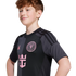 A young person with wavy reddish-brown hair wears a black and grey Inter Miami soccer jersey featuring a pink team crest and Royal Caribbean logo.