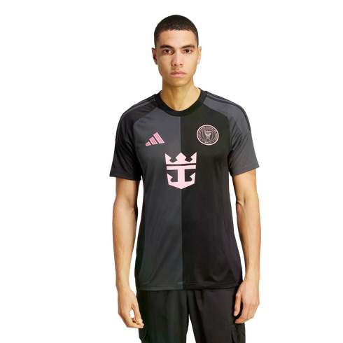 A man models a two-toned grey and black Inter Miami CF soccer jersey featuring pink logos on a plain white background.