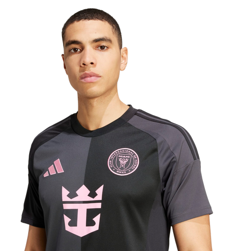 A man wears a black and gray Inter Miami soccer jersey with pink logos, including the Adidas and Royal Caribbean symbols, against a white background.