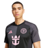 A man wears a black and gray Inter Miami soccer jersey with pink logos, including the Adidas and Royal Caribbean symbols, against a white background.