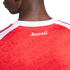 A close-up of the back of a red Arsenal jersey with a white collar, featuring a repeating "A" pattern and "Arsenal" printed in white gothic font below the neckline.