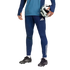 A person in blue athletic wear and black soccer cleats holds a soccer ball under their arm against a solid black background.