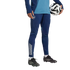 Person in blue Arsenal FC training gear and black soccer cleats holding a soccer ball against a black background.