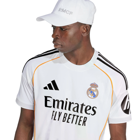 A man wearing a white Real Madrid football jersey and matching white baseball cap against a plain white background.