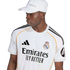 A man wearing a white Real Madrid football jersey and matching white baseball cap against a plain white background.