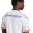 The back of a man wearing a white FC Bayern München soccer jersey with navy lettering and orange-patterned sleeves.