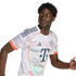 A young Black man with curly hair wearing a white patterned FC Bayern Munich soccer jersey, looking to his left in a dynamic running pose.