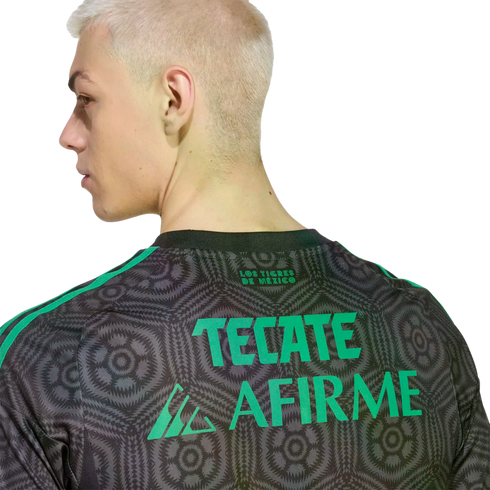 Side profile of a blonde man wearing a grey patterned jersey with green "TECATE" and "AFIRME" text on the back. Solid black background.