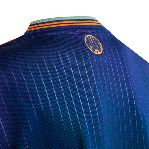 Close-up of the back neck of a blue pinstriped jersey featuring an orange circular logo and a green and orange striped collar.