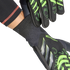 Close-up of black and neon green goalkeeper gloves being put on, highlighting the textured fingers and ribbed wrist cuff against a black background.
