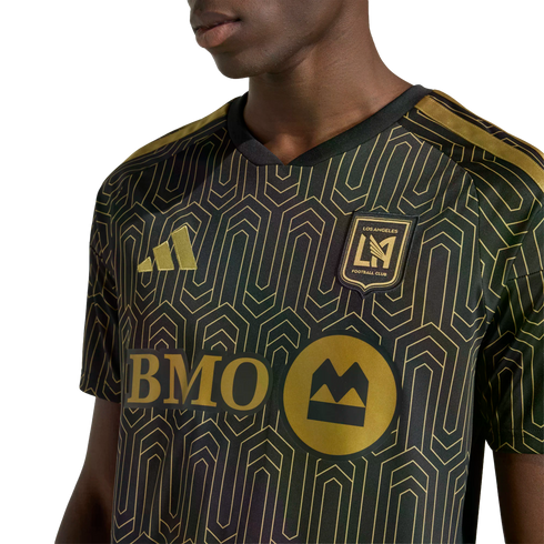 A person wearing a black and gold LAFC soccer jersey with an intricate geometric pattern. Features the gold Adidas logo, team crest, and BMO sponsor logo.