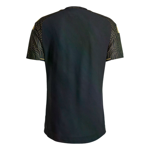 Back view of a black soccer jersey with gold geometric patterns on the sleeves and shoulders. Gold 'LOS ANGELES' text is printed at the back neck.