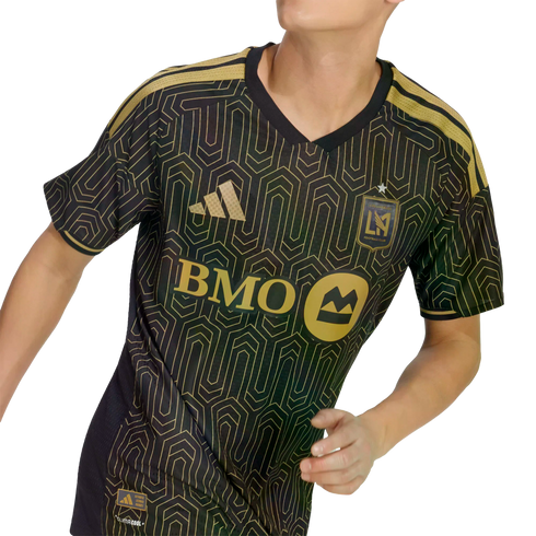 A person wears a black and gold Los Angeles FC soccer jersey featuring an Art Deco geometric pattern, the BMO sponsor logo, and the team crest.