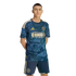A man models a navy blue and gold Philadelphia Union soccer kit featuring historic Philadelphia-themed graphics, standing against a black background.