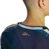 A close-up back view of a person's head and neck wearing a navy blue jersey with a small rattlesnake logo and a light blue and tan striped collar.