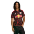 A man wearing a New York Red Bulls soccer jersey with red lightning patterns and black jeans against a black background.