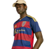 A man in a beige cap and a navy and red striped Real Salt Lake soccer jersey with yellow accents, posed against a black background.
