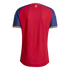 Back view of a red athletic jersey with blue sleeves, yellow shoulder stripes, and a small gold lion crest centered below the neckline.