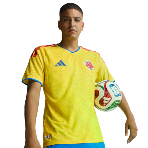 Man in a yellow Colombian national team soccer jersey, holding a soccer ball against a black background.