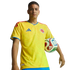 Man in a yellow Colombian national team soccer jersey, holding a soccer ball against a black background.