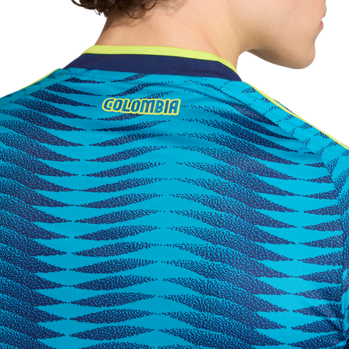 Close-up of the back of a teal and blue patterned soccer jersey with "COLOMBIA" in yellow text near the lime green and navy collar.