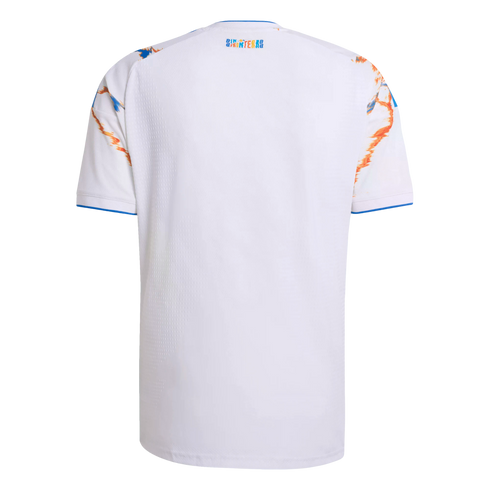 Back view of a white soccer jersey featuring blue and orange graphic shoulders, blue trim, and a small colorful logo below the collar.