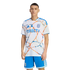 A man models a San Diego FC soccer kit with a white jersey featuring orange and blue abstract patterns and a DIRECTV logo, paired with blue shorts.