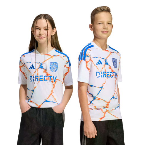 Two youth models wear white San Diego FC soccer jerseys with an orange and blue marbled pattern and the DIRECTV logo. They are posed against a black background.