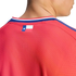 Close-up of a person wearing a red textured sports jersey with a small Texas flag logo on the upper back, just below the striped collar.