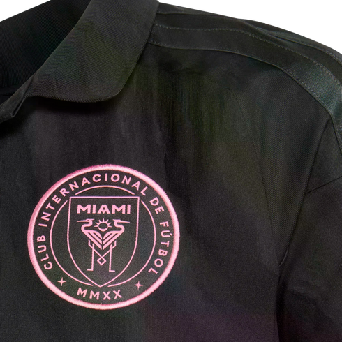 Close-up of a black Inter Miami CF soccer jersey featuring a pink embroidered team crest on the chest.