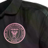 Close-up of a black Inter Miami CF soccer jersey featuring a pink embroidered team crest on the chest.