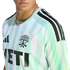 Close-up of a man wearing a light green and white striped Austin FC soccer jersey with a silver chain, set against a black background.