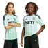 Two children pose in matching mint green and white striped Adidas soccer jerseys with "YETI" branding against a black background.