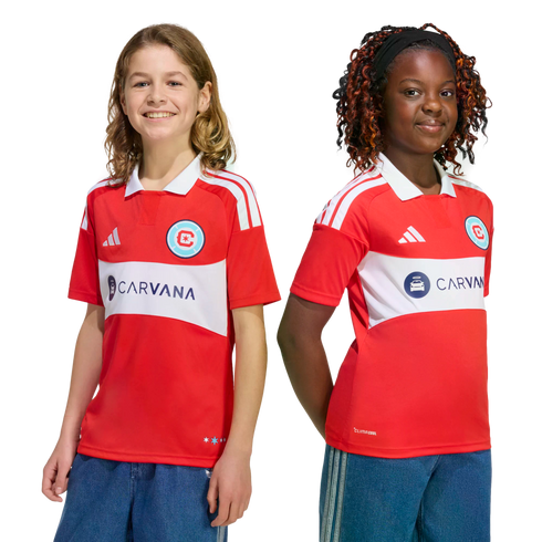 Two smiling children wearing red and white Chicago Fire FC soccer jerseys with the Carvana sponsor logo.